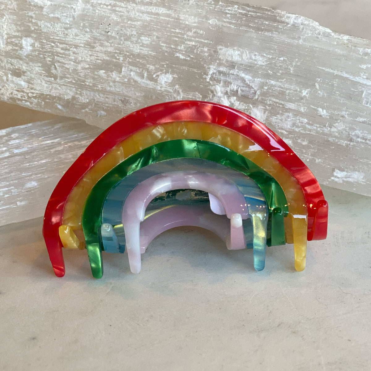 Rainbow Hair Clip shaped like a colorful rainbow with glossy, marbled segments in red, yellow, green, blue, and purple, displayed against a neutral background.