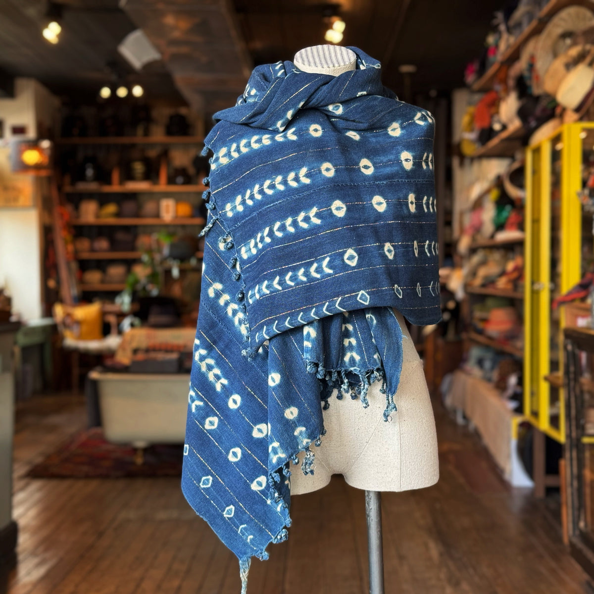 Vintage Indigo Mud Cloth Scarf No. 3 draped on a mannequin with a rich indigo blue color and traditional white geometric mud cloth patterns in a cozy boutique setting.