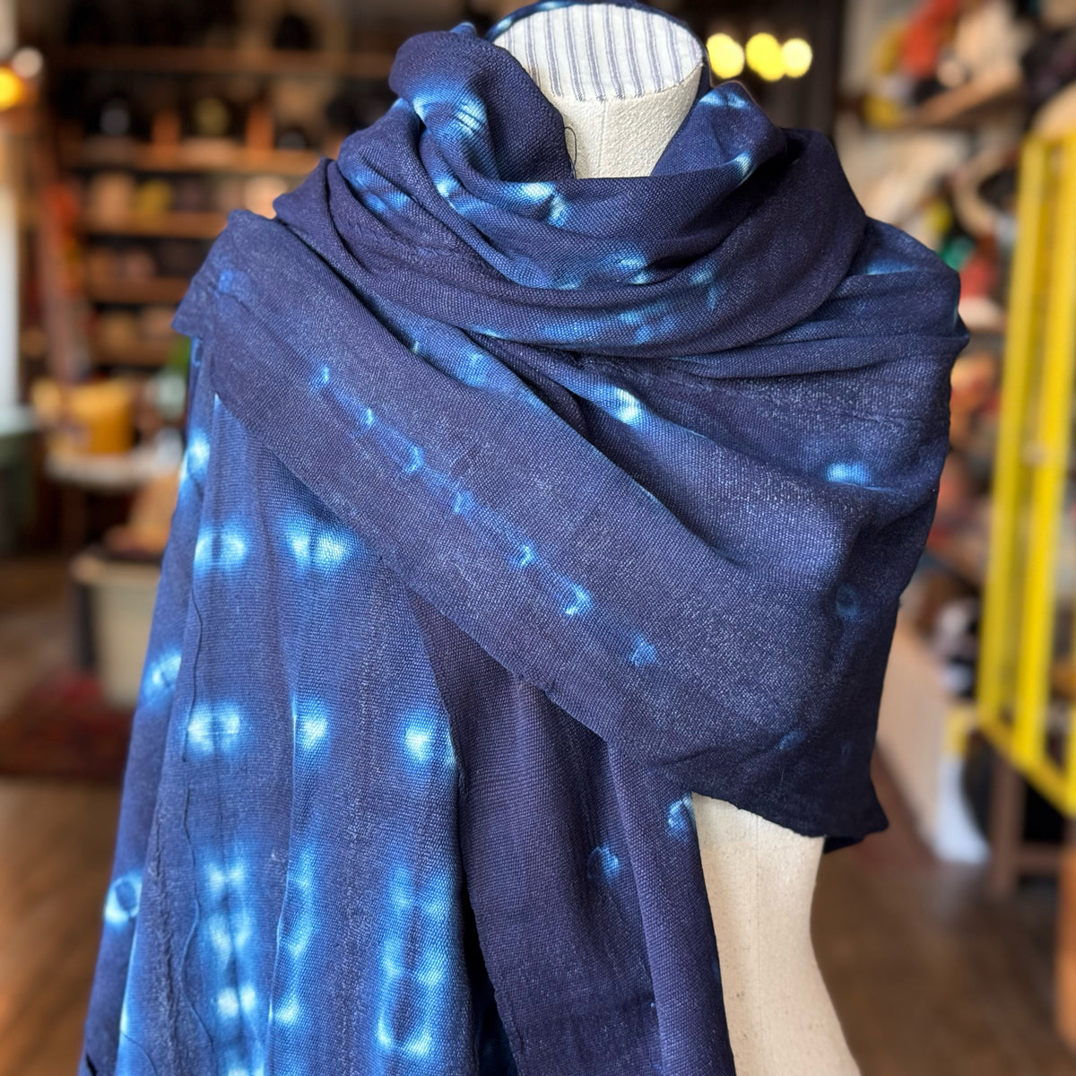 A soft, patterned indigo scarf draped on a mannequin, showcasing the unique tie-dye design and rich blue tones of the Vintage Indigo Mud Cloth Scarf No.6.