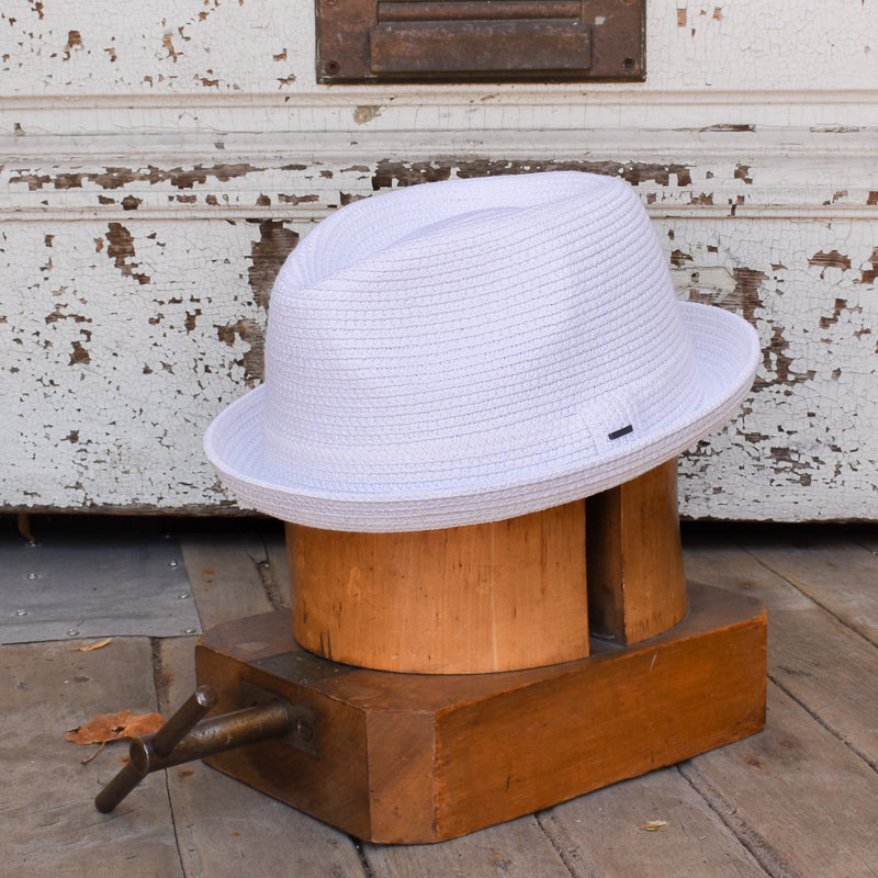 Billy white woven fedora hat displayed on a wooden hat block against a rustic background, showcasing its clean design and structured brim on fifth style.