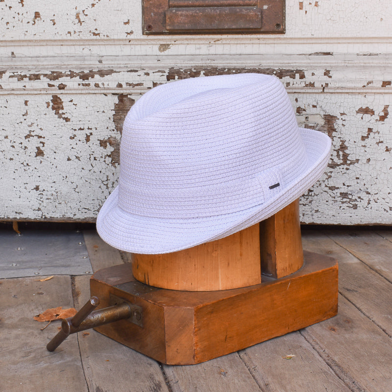 White woven fedora hat named Billy displayed on a vintage wooden hat block against a rustic white-painted wooden background.