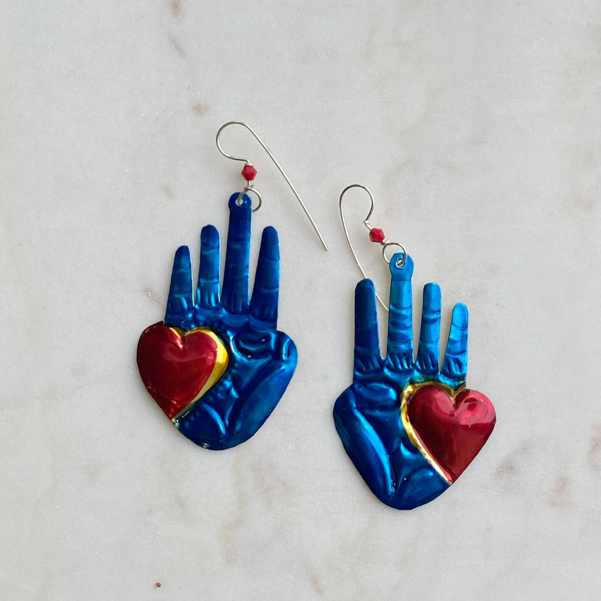 Pair of Blue Hand Earring with raised fingers and vibrant red heart accents, featuring shiny metallic blue finish and delicate silver hooks for wearing.
