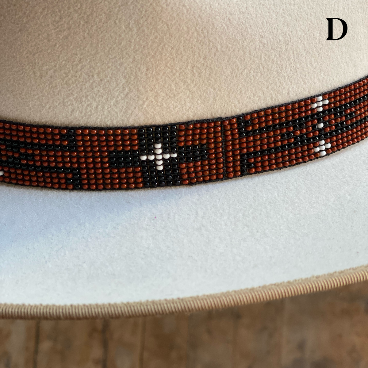 Close-up of a beige hat with a decorative Beaded Hat Band featuring a pattern of black, white, and brown-colored beads, designed as an accessory for brim hats.