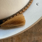 Close-up of a cream-colored hat featuring a detailed Braided Horsehair Hat Band with natural brown and black tones and a horsehair tassel accent, stylish accessory for hats.