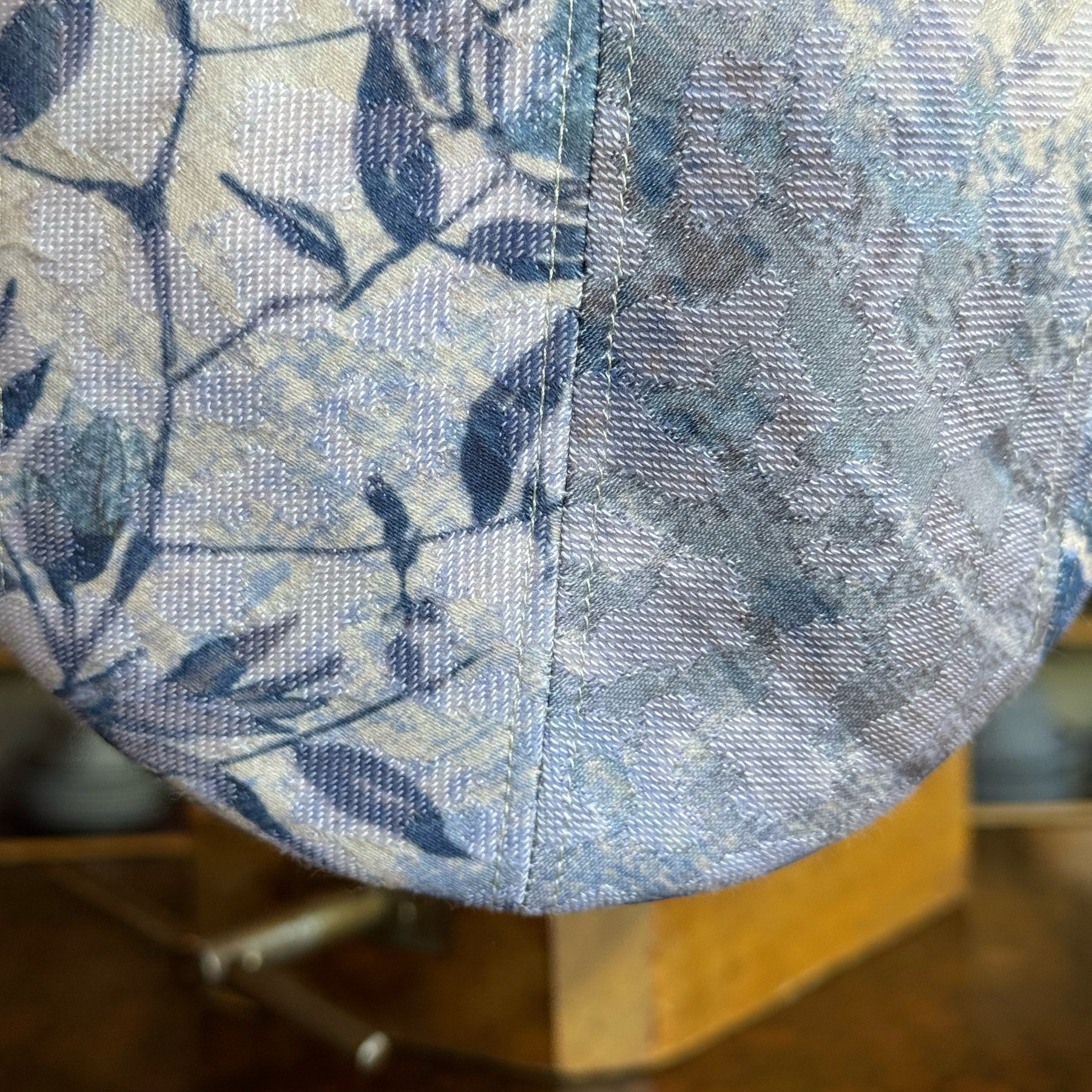 Close-up detail of the textured fabric with leaf pattern in soft blue and beige tones on the Cloud Leopard 2-Panel Ivy Cap by Brim on Fifth.