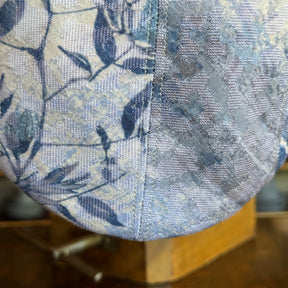 Close-up detail of the textured fabric with leaf pattern in soft blue and beige tones on the Cloud Leopard 2-Panel Ivy Cap by Brim on Fifth.