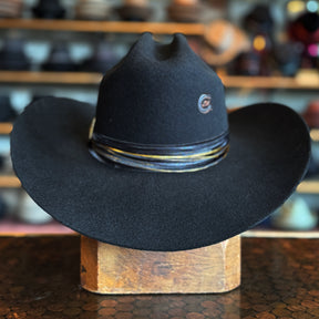Black wide-brimmed hat with a decorative band displayed on a wooden block, showcasing the classic style of the Daredevil hat.