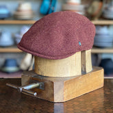 Essential 2-Panel Ivy Cap in a warm rust color displayed on a wooden hat block, showcasing its classic flat cap design and textured fabric perfect for stylish accessories.