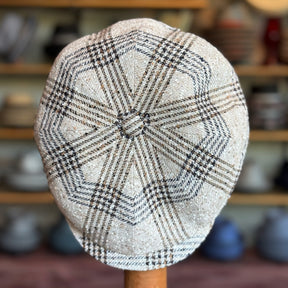 Top view of a textured linen newsboy cap with a checkered pattern in neutral tones, showcasing the detailed stitching and classic design of the Textured Linen Hatteras.