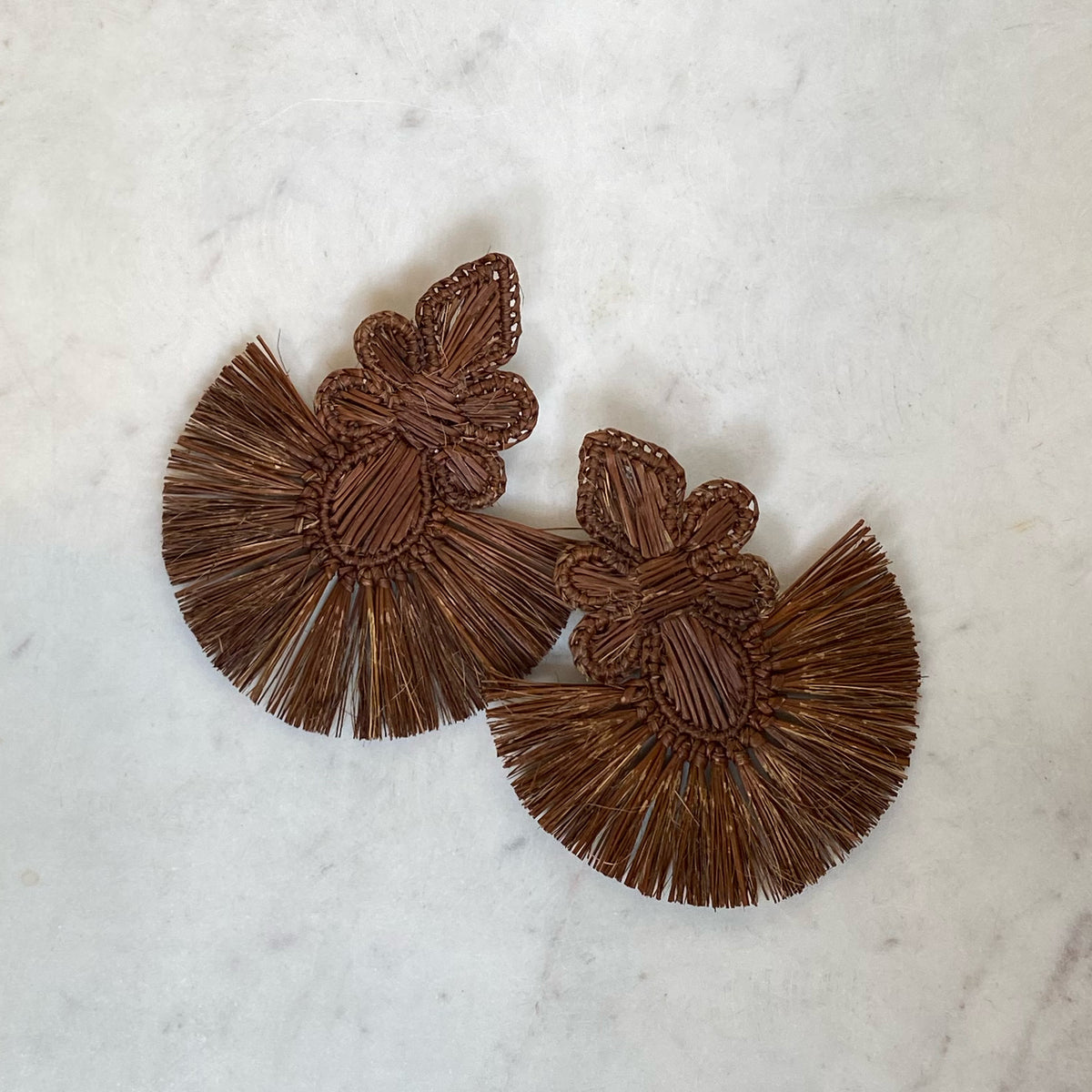 Pair of brown woven Iraca Tower Earring with intricate floral design and fan-shaped fringe detailing, showcasing natural artisanal craftsmanship.