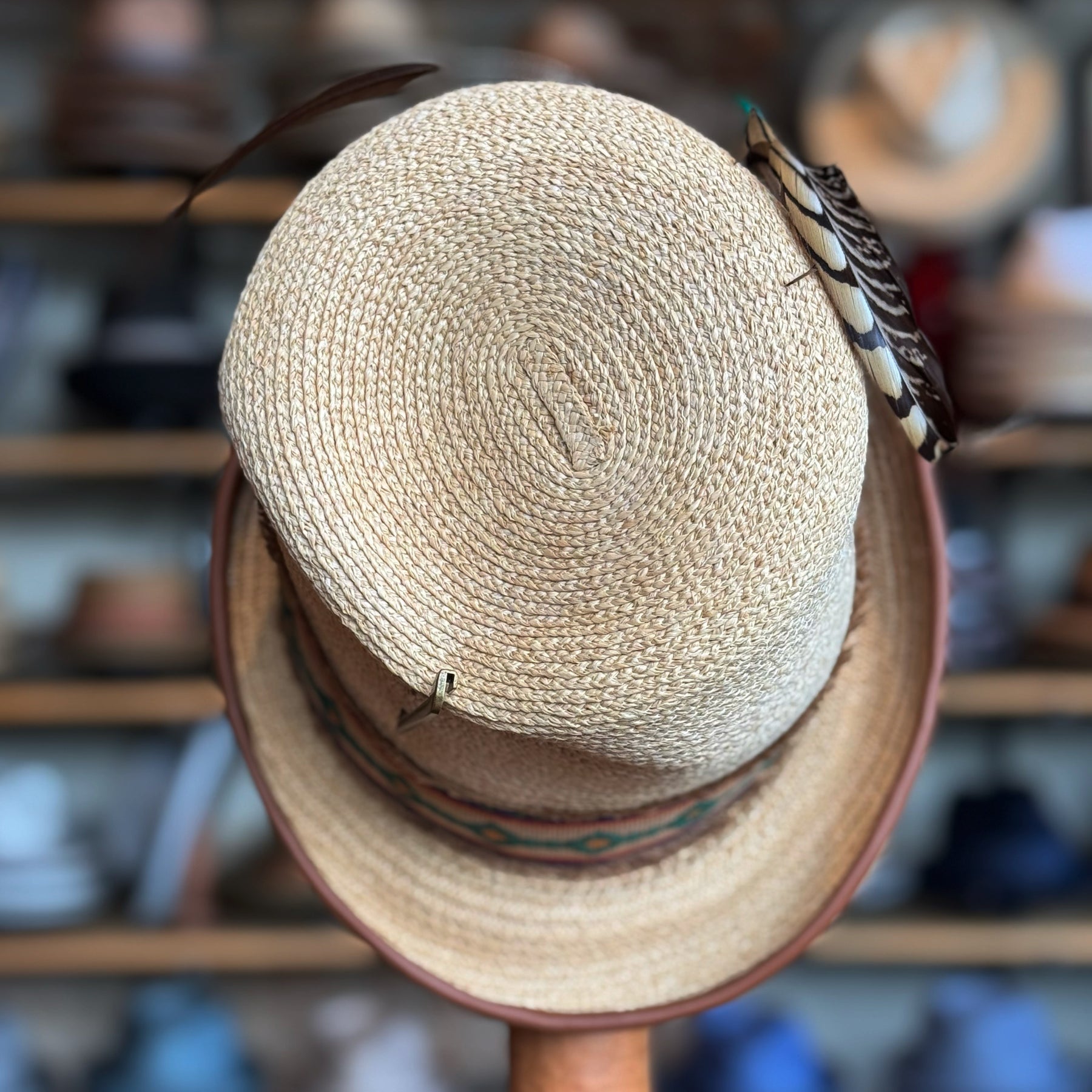 Luna Straw Top Hat with woven natural straw material, decorative feather accents, and a patterned band, perfect for stylish accessory lovers.