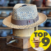 Maize Panama Fedora hat with braided straw design featuring natural and black and a brown fabric band, displayed on a wooden stand in a hat shop.
