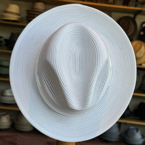 Max white wide brim hat with a structured crown, crafted from woven material, displayed in a hat shop among various other styles.
