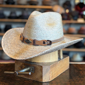 Monterrey Bay straw cowboy hat with leather band detail displayed on a wooden hat block in a hat shop setting