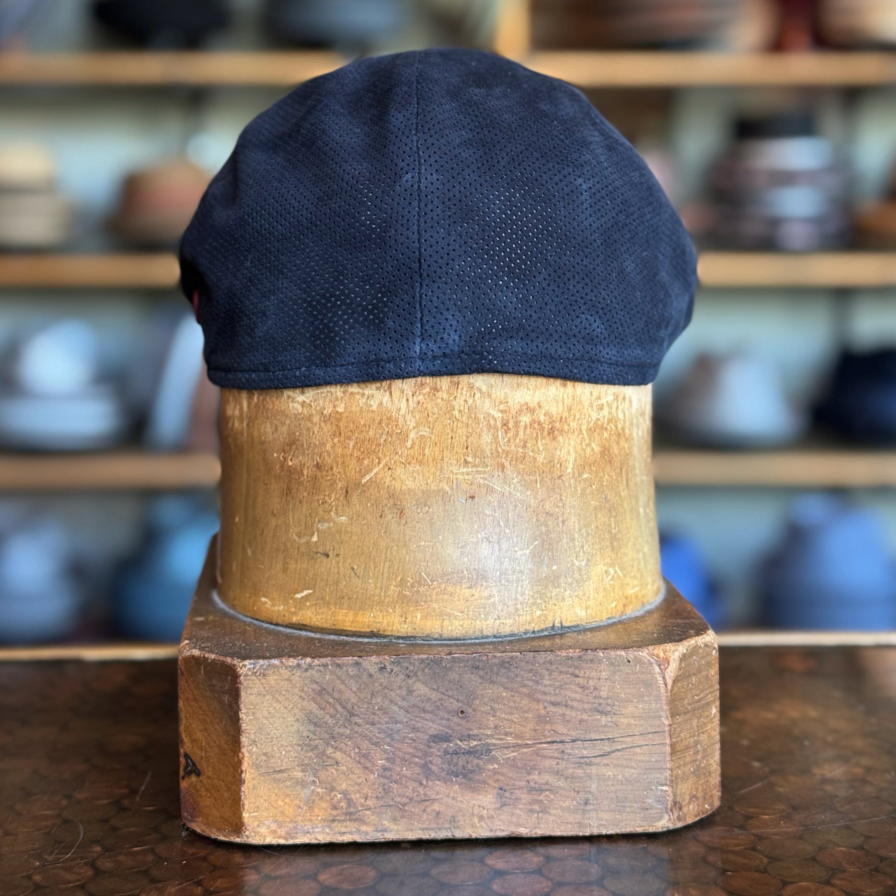 Back view of a navy Summer Suede 6-Panel Cap displayed on a wooden hat block, showcasing the cap’s smooth suede texture and classic design.