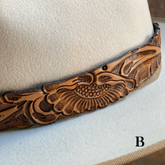 Close-up of a natural tooled leather hat band with detailed floral and leaf patterns on a light-colored hat, showcasing the craftsmanship of the Tooled Leather Hat Band accessory.
