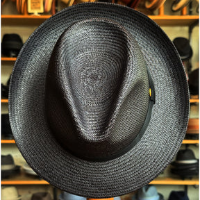 Torino black woven hat with a structured crown and wide brim, displayed against a background of various other hats on wooden shelves.