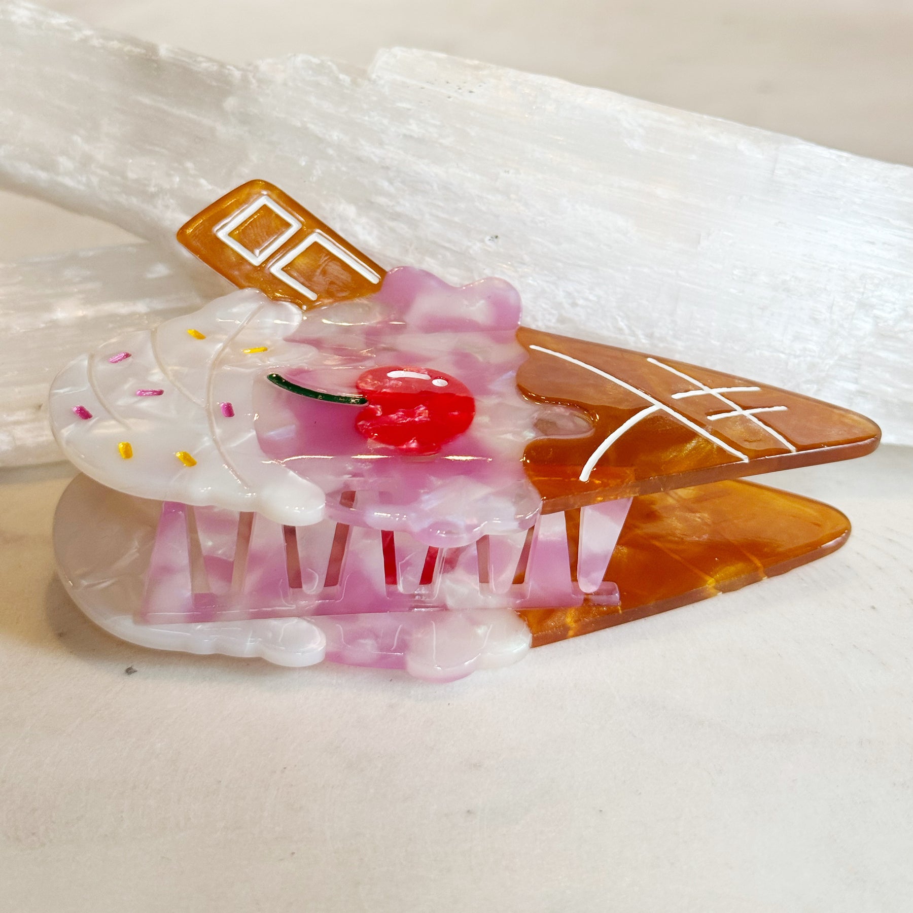 Ice Cream Hair Clip designed to resemble a colorful ice cream cone with white, pink, and amber tones, featuring a red cherry detail and decorative sprinkles.
