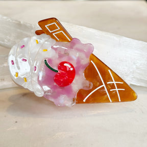Clear plastic Ice Cream Hair Clip shaped like an ice cream cone with white swirl, colorful sprinkles, a pink topping, and a red cherry detail.