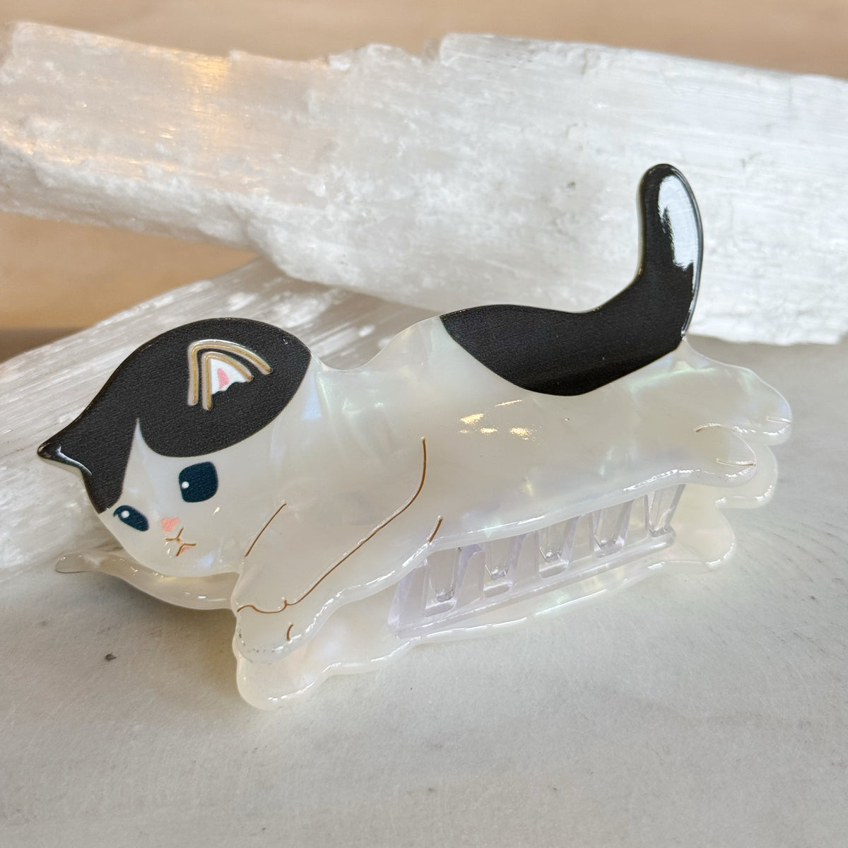 Kitty Hair Clip featuring a playful black and white cat design in a relaxed pose made from glossy, translucent material with fine detailing on a claw-style clip.