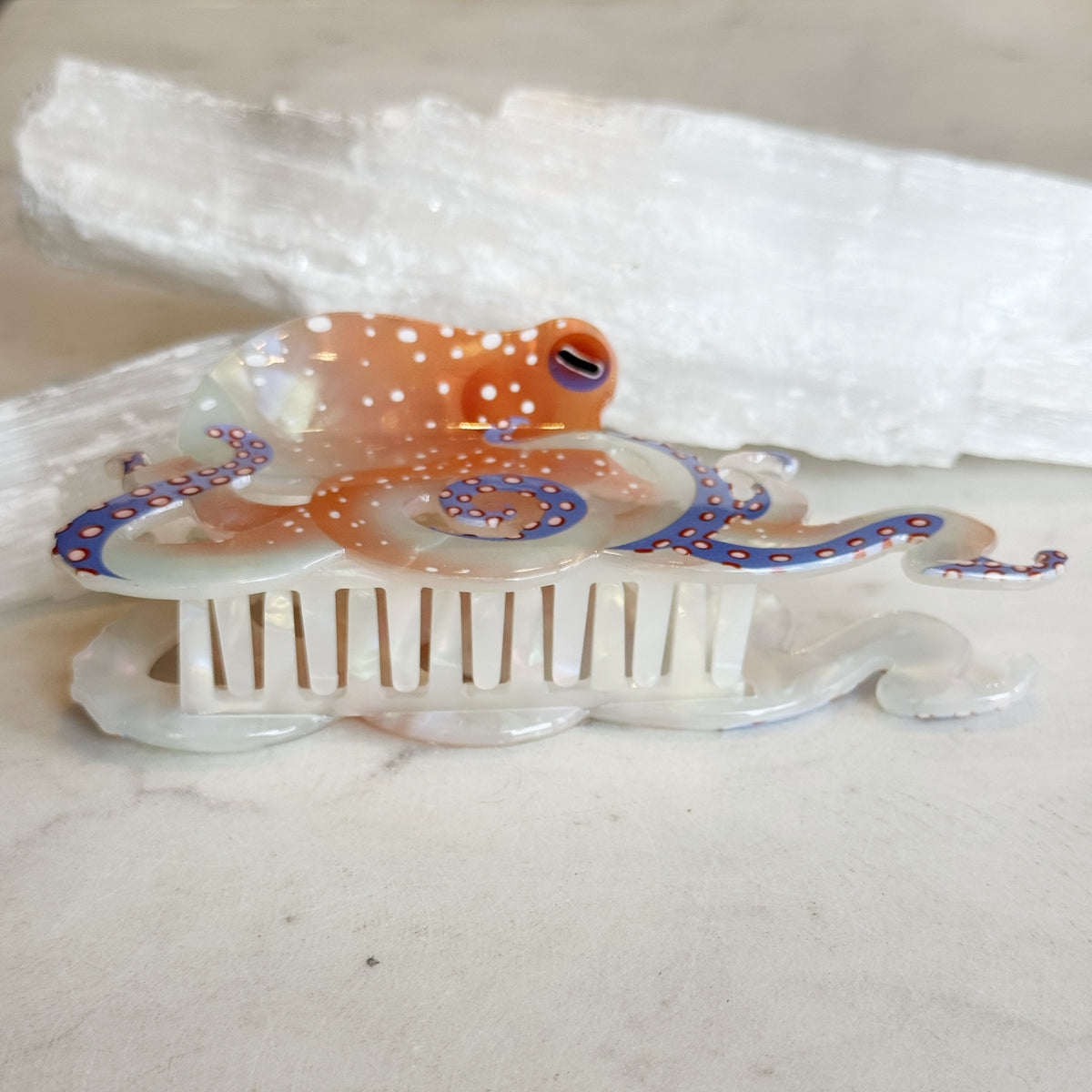 Octopus Hair Clip featuring a detailed translucent design with orange and purple accents shaped like an octopus resting on a comb with fine teeth.