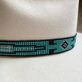 Close-up of a white hat featuring a decorative Beaded Hat Band with turquoise, black, and white geometric patterns, ideal for enhancing fedoras and other brim hats.