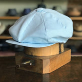 Light blue Linen Big Apple newsboy cap displayed on a wooden hat block, showcasing its soft fabric and classic structured design.