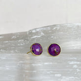 Rose Cut Mohave Turquoise Studs featuring vibrant purple stones with gold-tone settings, displayed on a textured light surface with a minimalist background.